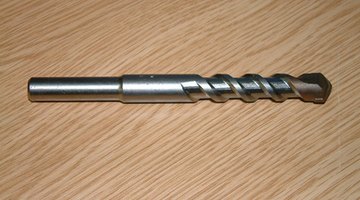 Use a masonry bit in a hammer drill and drive pins to attach the floor plates to the concrete.