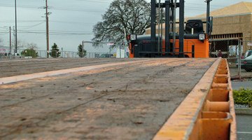 Flatbed truck with trailing forklift.