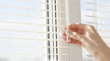 Close-up of woman's hands closing blinds.