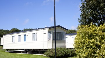 A mobile home surrounded by grass and trees.