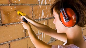 Woman drills into brick wall